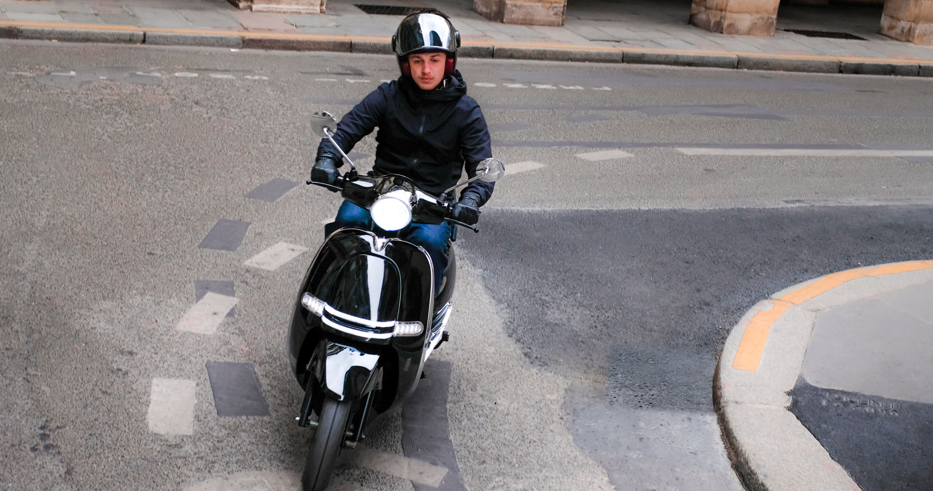Jeune homme sur un scooter 125 électrique en plein virage dans les rues de Paris