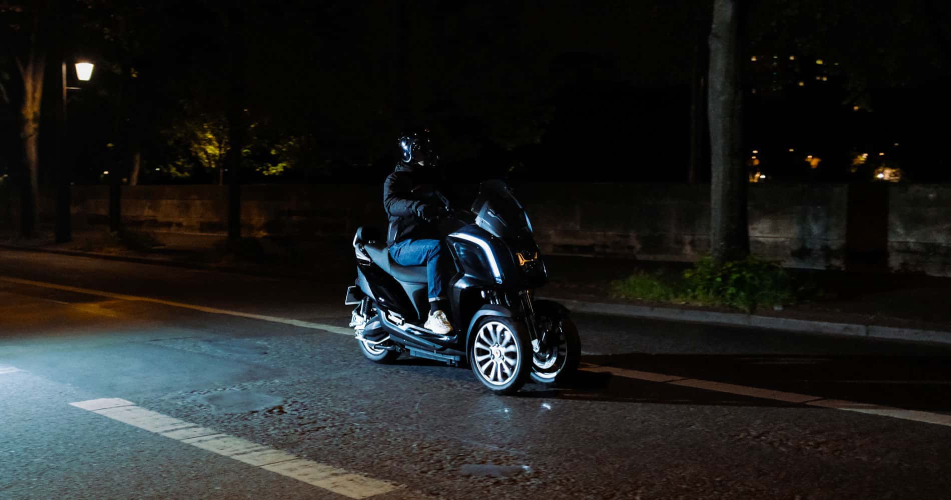 Un scooter 3 roues électrique circulant de nuit dans une petite ville