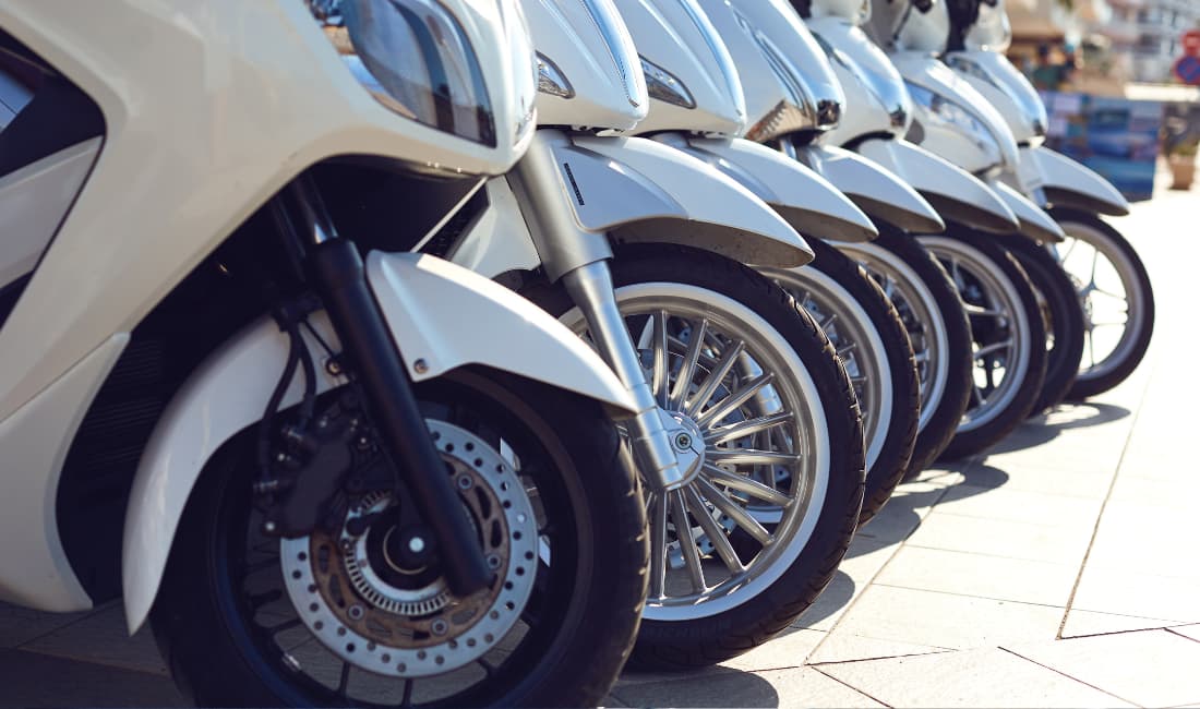 Une série de scooters alignés sur un parking